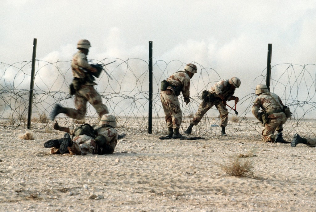 Members of the 1st Battalion, 325th Airborne Infantry Regiment, make their way through concertina wire during a live fire demonstration for Saudi Arabian national guardsmen. The demonstration is taking place during Operation Desert Shield. Source: Wikimedia Commons
